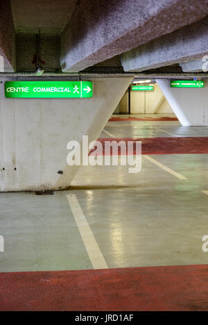 Les panneaux lumineux indiquant la direction du centre commercial dans un vieux parking souterrain décrépi. Banque D'Images