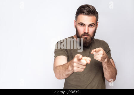 Hey You ! Portrait d'homme barbu graves avec t-shirt vert foncé à l'arrière-plan gris clair. studio shot. Banque D'Images