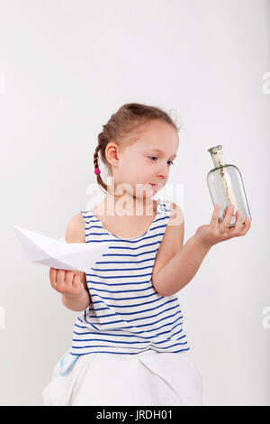 Cute little girl trouver message secret en bouteille en verre. Bacgkround isolé sur fond blanc Banque D'Images