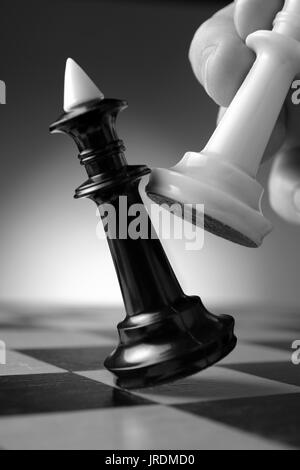 Image représentant conceptuel faisant un geste stratégique avec une main le déplacement d'une pièce d'échecs sur un échiquier lors d'un jeu d'adresse Banque D'Images