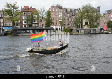 Amsterdam, Pays-Bas . 5 août 2017. Deux hommes battant le drapeau arc-en-ciel de leur bateau de plaisance sur la rivière Amstel pour célébrer la gay prIde d'Amsterdam. Credit : Patricia Phillips/Alamy live news Banque D'Images