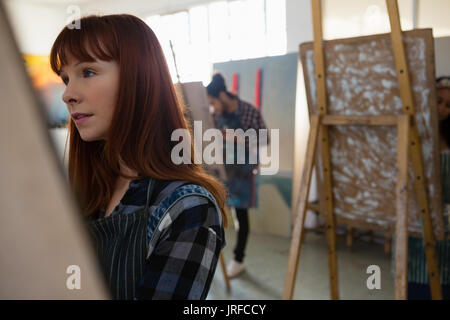 Close up of woman painting on easel in art class Banque D'Images