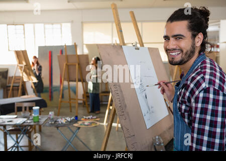 Portrait of smiling man peinture sur papier dans la classe d'art Banque D'Images