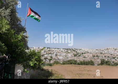 Une vue sur le centre de la ville d'Hébron en conflit comme vu à partir d'un quartier palestinien donnant sur elle avec un drapeau palestinien battant de défi Banque D'Images