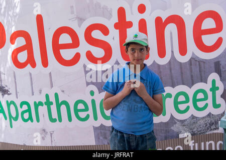 Jeune garçon palestinien debout devant un signe qui protestent contre la fermeture d'une rue centrale à Hébron, en Cisjordanie, Territoires Occupés Banque D'Images