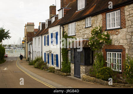 Seul un homme âgé marche dans une rue pittoresque de maisons mitoyennes à la plage dans le village de Warsash sur une journée terne Banque D'Images