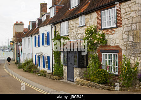 Seul un homme âgé marche dans une rue pittoresque de maisons mitoyennes à la plage dans le village de Warsash sur une journée terne Banque D'Images