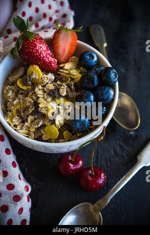 Petit-déjeuner sain avec oatmeals et baies organiques - blueberry et fraise sur table en bois foncé avec copyspace Banque D'Images