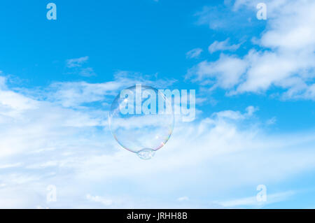 Grosse bulle flottant dans un ciel d'été bleu clair avec des nuages blancs. Banque D'Images