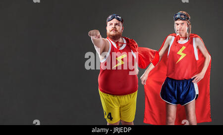 Deux drôles d'hommes en costumes de super-héros. Les personnes minces et de graisses Banque D'Images