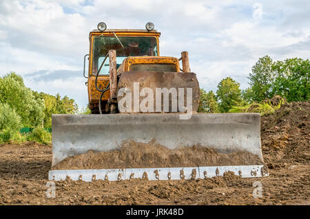 Ancien travail d'excavateur le défrichage au coucher du soleil d'une journée ensoleillée. Banque D'Images