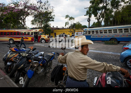 Antigua, Guatemala - 16 Avril 2014 : scène de rue dans la ville d'Antigua, au Guatemala, avec un homme au premier plan et deux bus sur la zone de Banque D'Images