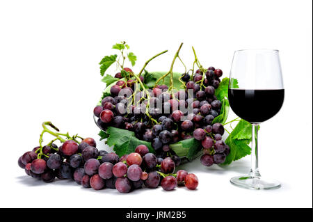 Verre de vin rouge frais et grappes de raisins photographié sur un fond blanc. Banque D'Images