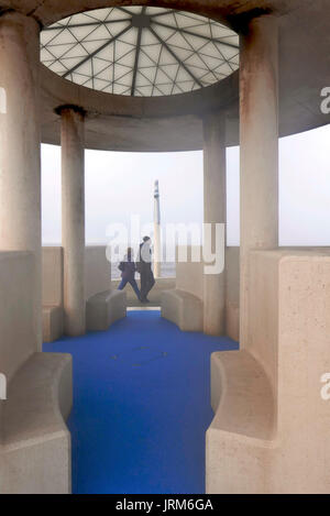 L'homme et la femme dans des vêtements d'hiver en passant devant l'atrium de verre béton couverte sur promenade en bord de mer dans la brume Banque D'Images