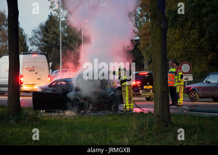 ACHTERHOEK, Pays-Bas - OCT 29, 2015 : les pompiers à proximité d'une carcasse de voiture brûlée. Banque D'Images