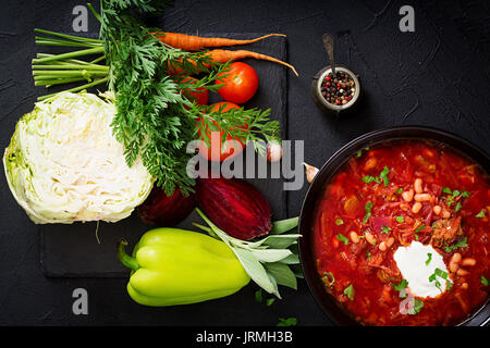 Bortsch Russe Ukrainien traditionnel avec des haricots blancs sur le bol noir et ingrédients pour le borchtch. Mise à plat. Vue d'en haut. Banque D'Images