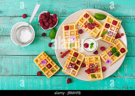 Belgique gaufres avec des framboises et du yogourt sur la plaque. Mise à plat. Vue d'en haut Banque D'Images