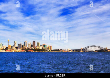 Paysage urbain de la ville de Sydney CBD hautes tours à bureaux et points de repère à destination du tourisme le Sydney Harbour Bridge vu depuis la mi harbour dans un ciel ensoleillé d Banque D'Images