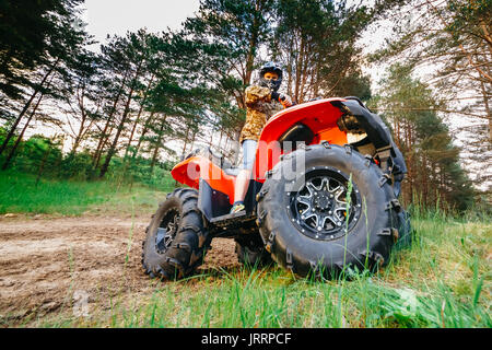 L'homme sur l'ATV Quad fonctionnant en voie de boue Banque D'Images