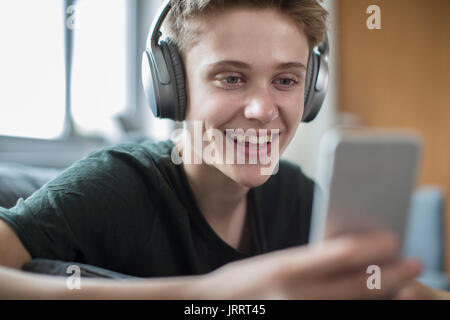 Teenage Boy Streaming de musique à partir d'un téléphone portable sur un casque sans fil Banque D'Images