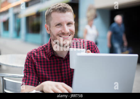 Portrait of Young Man at Outdoor Cafe Working On Laptop Banque D'Images