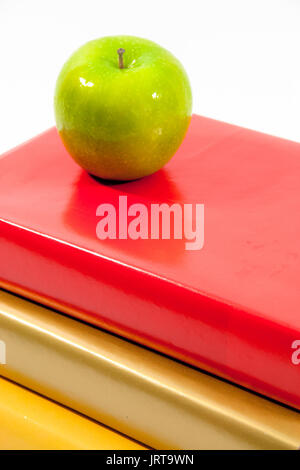 Une pomme verte est situé au sommet d'une pile de trois livres. Banque D'Images