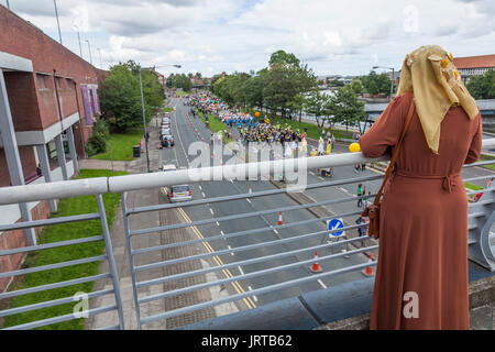 Légende 62/150 une femme asiatique dans un foulard regarde le Stockton International Riverside Festival défilé d'une passerelle sur Riverside Route Banque D'Images