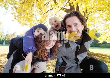 Donner aux enfants les parents piggyback ride à l'automne jaune park Banque D'Images