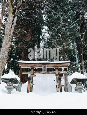 Temple japonais Nozawa Onsen gates dans le cadre de chutes de neige fraîche avec de beaux grands arbres. Banque D'Images
