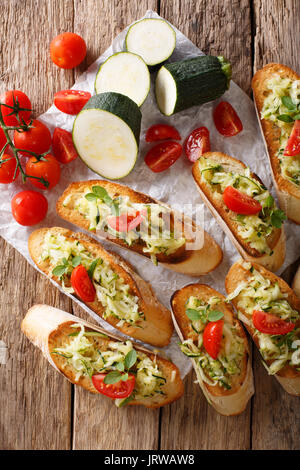 Bruschetta italienne avec les courgettes et tomates close-up et les ingrédients sur la table. Vue verticale d'en haut Banque D'Images