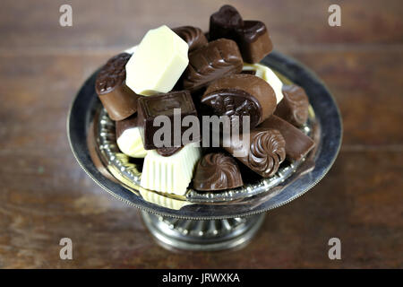 Chocolat pralines belge dans un bol en argent sur fond de bois rustique Banque D'Images