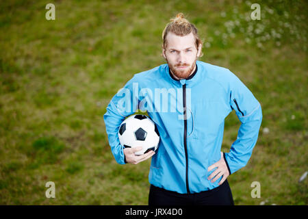Portrait de jeune entraîneur confiant posant avec balle au terrain de soccer Banque D'Images