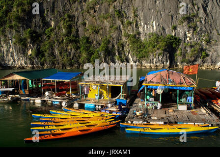 Kayak passé un village de pêcheurs flottant dans la baie d'Halong. fish farm village entre les montagnes de calcaire karstique dans le parc national de Cat Ba, ha long halong,ba Banque D'Images