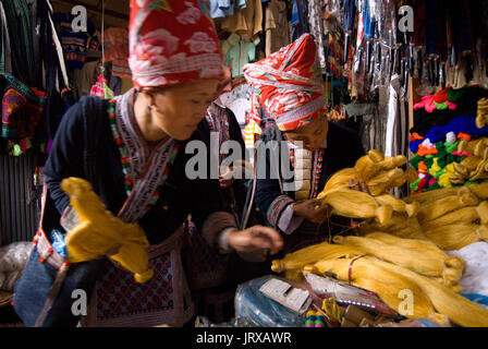 Dao rouge femmes hmong fabriquent et vendent des vêtements et de l'artisanat tribal iniside le marché de Sapa, province de Lao Cai, Vietnam Banque D'Images