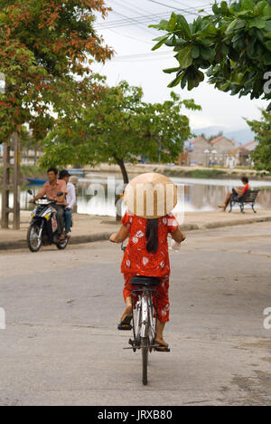 Les cyclistes femme sur la promenade de la rivière Thu Bon à Hoi An au Vietnam. Woman with hat vietnamise typique. Banque D'Images