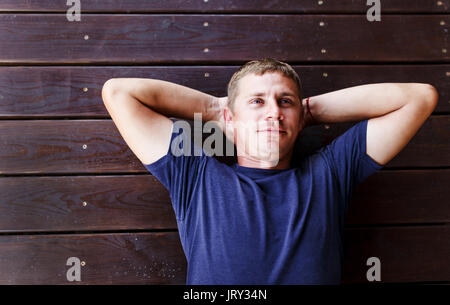 Jeune homme étendu et reposant sur une terrasse en bois à l'extérieur. Banque D'Images