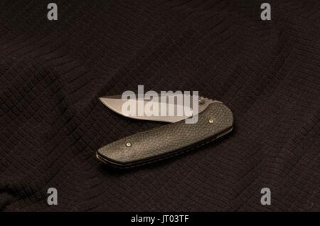 Couteau noir en courbe sur un fond noir. Banque D'Images