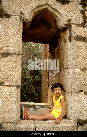 Jeune fille assise seule à l'intérieur de la fenêtre en pierre au Fort Chitradurga, Karnataka, Inde, Asie Banque D'Images