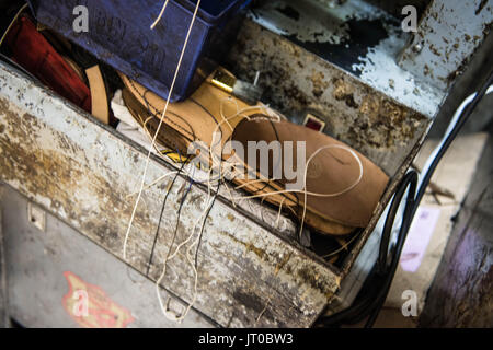 Gros plans d'outils de réparation de chaussures et de chaussures dans un atelier de cordonnier traditionnel, mettant en évidence les semelles, l'équipement de réparation et le processus de résineux Banque D'Images