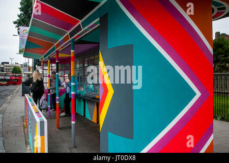 Personnes en attente d'un bus à l'intérieur d'un abri bus peintes de couleurs vives, Brighton, Sussex, UK Banque D'Images