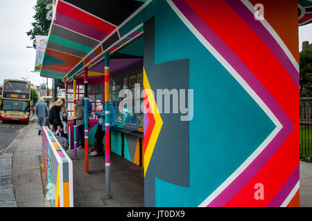 Personnes en attente d'un bus à l'intérieur d'un abri bus peintes de couleurs vives, Brighton, Sussex, UK Banque D'Images