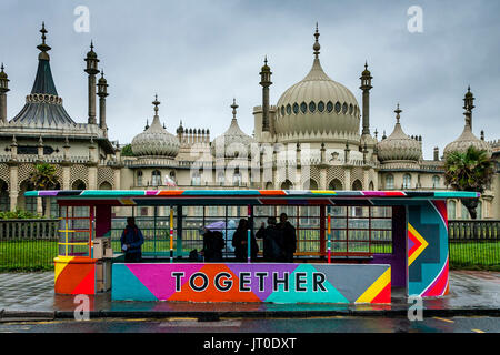 Personnes en attente d'un bus à l'intérieur d'un abri bus peintes de couleurs vives, Brighton, Sussex, UK Banque D'Images