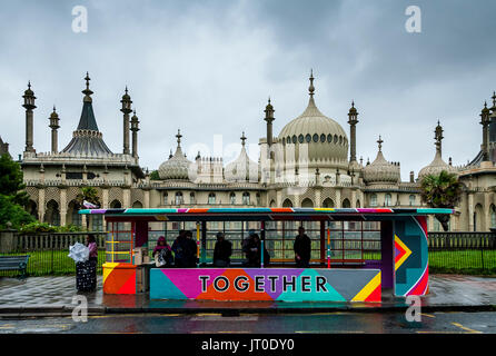 Personnes en attente d'un bus à l'intérieur d'un abri bus peintes de couleurs vives, Brighton, Sussex, UK Banque D'Images