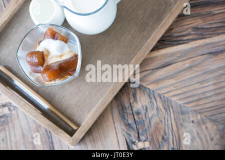 Forme de coeur café congelé des cubes de glace et glace vanille dessert avec du lait sur la table en bois Banque D'Images