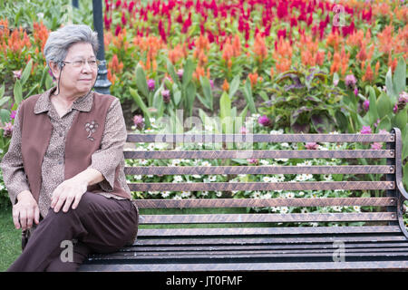 Aîné asiatique femme assis sur un banc dans le jardin. personnes âgées de sexe féminin senior et vous reposer dans le parc Banque D'Images