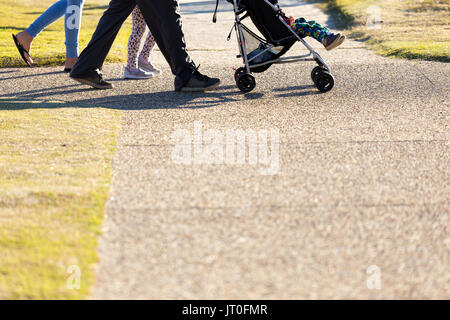 Ci-dessous une photo de la taille d'une famille de quatre personnes, dont un bébé dans un landau, la marche et l'exercice sur un sentier du parc de la ville. Banque D'Images