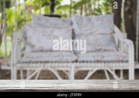 Swing en osier rotin blanc banc avec coussin bleu et un oreiller dans jardin avec table en bois pour la mise au point sélectionné afficher votre style de vie relaxant au produit. Banque D'Images