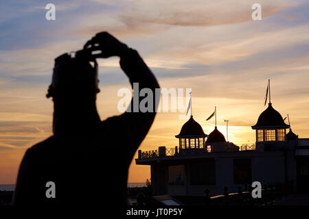 Herne Bay, Kent, UK. 7 Août 2017 : Météo France. Lever du soleil à Herne Bay seafront lors d'une fraîche matinée. La statue en bronze de l'artiste Stephen Melton en mémoire d'Amy Johnson qui a disparu au large de la côte de Herne Bay en janvier 1941 se tourne vers l'est pour le kiosque. L'été humide devrait se poursuivre pour les prochains jours. Credit : Alan Payton/Alamy Live News Banque D'Images