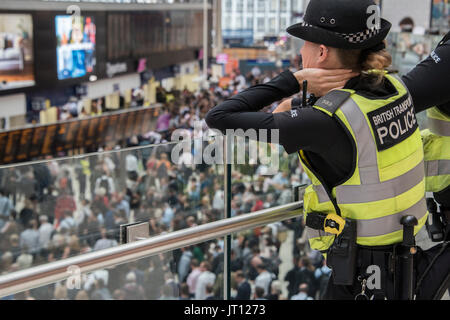 Londres, Royaume-Uni. 07Th Aug, 2017. La police des transports avec un Taser regarder depuis la mezzanine comme foules atteindre un pic dans le grand hall après 6 heures - dix plates-formes sont fermées à la gare de Waterloo pour tout le mois d'août pour une mise à niveau de plates-formes. Crédit : Guy Bell/Alamy Live News Banque D'Images