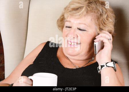 Portrait d'une vieille femme parlant au téléphone et assis sur table. À l'intérieur. Banque D'Images